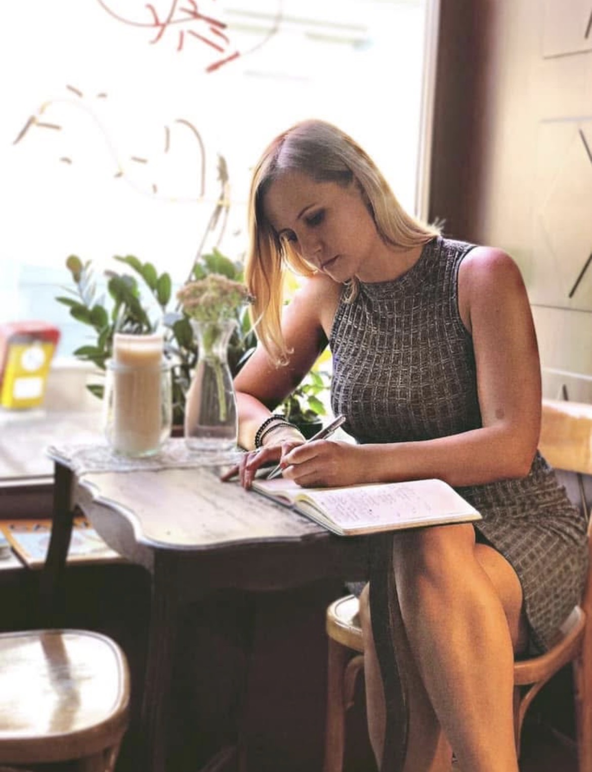 Sylvana Kozak writing in a notebook at a café table